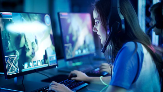 Professional Girl Gamer Plays in MMORPG/ Strategy Video Game on Her Computer. She's Participating in Online Cyber Games Tournament, Plays at Home, or in Internet Cafe. She Wears Gaming Headset. Une fille jouant à un jeu vidéo