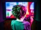 Un jeune garçon, manette à la main, jouant à un jeu vidéo ultracoloré sur un large moniteur TV.