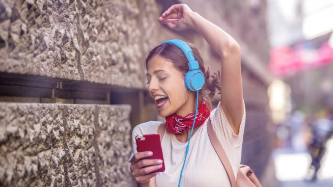 heardle-spotify-jeu-de-musique-en-ligne Une jeune femme dans la rue en train de chanter un morceau mystère du jeu musical en ligne Heardle