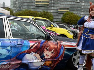 Une Japonaise en cosplay devant une voiture véhiculant la culture Itasha, ornée du personnage d’animé Daiwa Scarlet qu’elle incarne.