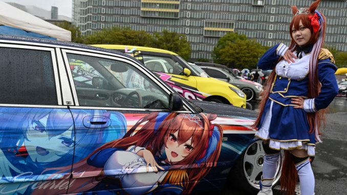 culture-itasha-japon-voiture-decoree-personnage-anime Une Japonaise en cosplay devant une voiture véhiculant la culture Itasha, ornée du personnage d’animé Daiwa Scarlet qu’elle incarne.