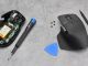 Une souris Logitech avec le capot ouvert et des matériels de réparation iFixit.