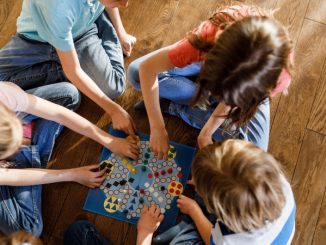 De jeunes enfants en train de jouer à des jeux de société, à même le sol.