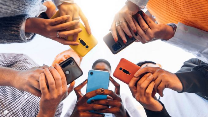 smartphone-pou-ado-criteres-choix-parents-rentree-jeux-mobiles Des jeunes en rond tenant chacun dans leurs mains un smartphone pour ado.