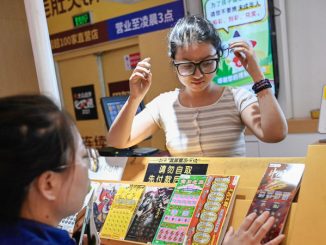 Une jeune Chinoise devant un stand de jeux de grattage.