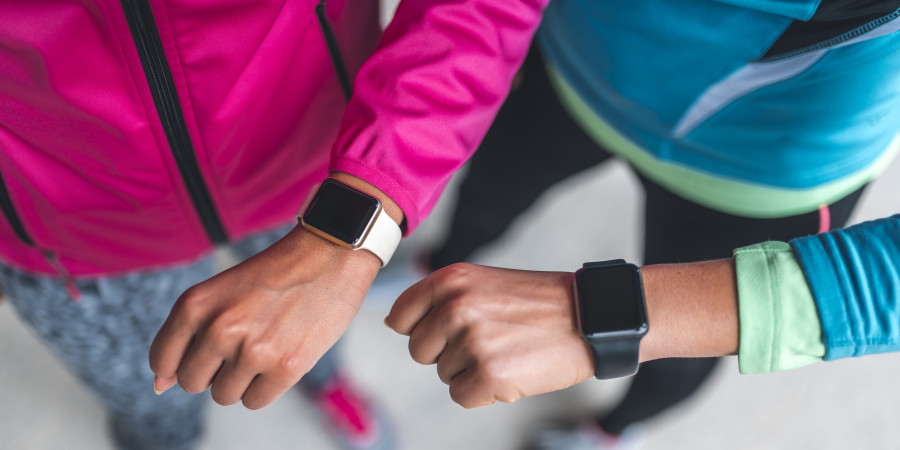 Deux femmes brandissant leurs poignets, enroulés de bracelet de montre connectée.