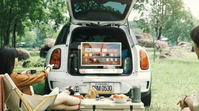 stanbyme-go-lg-televiseur-valise Un couple en pleine excursion en nature qui fait un partage d’écran de smartphone sur le téléviseur valise LG StanbyME Go.