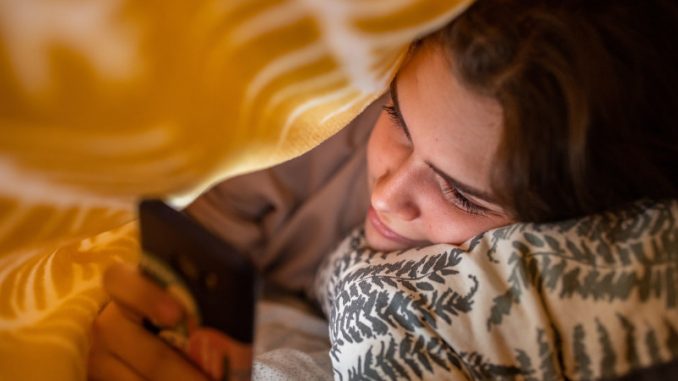 dependance-a-internet-internautes-groupes Une adolescente sous sa couverture en train de surfer furtivement sur son smartphone, illustrant parfaitement la dépendance à Internet des jeunes.