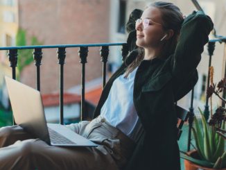 Une femme avec son PC portable en train de travailler sur le balcon d’un hôtel, une parmi les innombrables « digital nomads » voyageant à travers l’Europe.