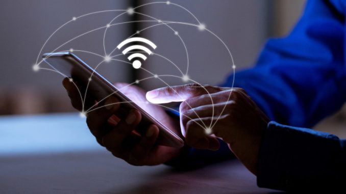 norme-wi-fi-7-perfomances-jeux-en-ligne Un homme manipulant un smartphone exploitant le haut début de la norme Wi-Fi 7